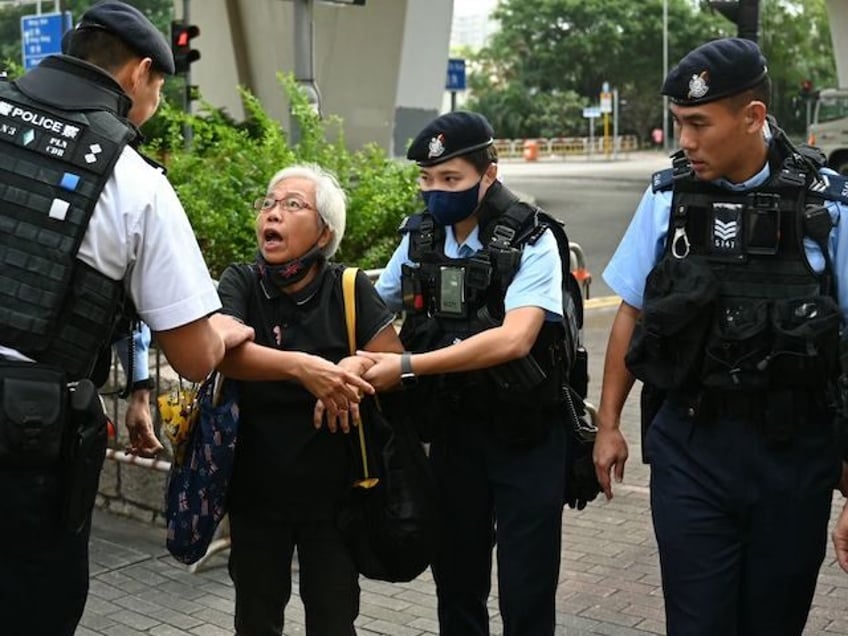 Pro-democracy activist known as Grandma Wong is escorted away by police outside court where Hong Kong's largest national security trial against 47 pro-democracy activists started its final arguments on November 29, 2023 more than 1,000 days since the case under the Beijing-imposed law began. (Photo by Peter PARKS / AFP)