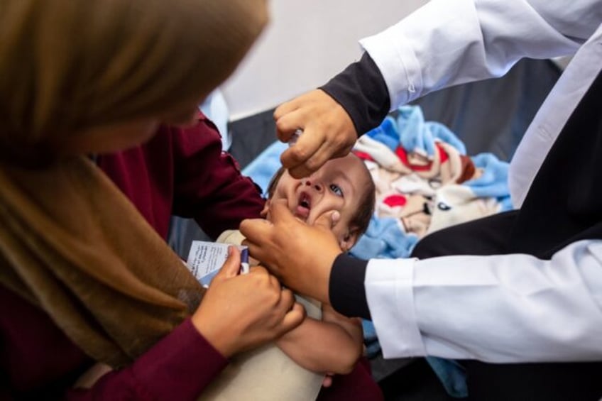 A nurse administers polio vaccine drops to a Palestinian child at Nasser Hospital in Khan