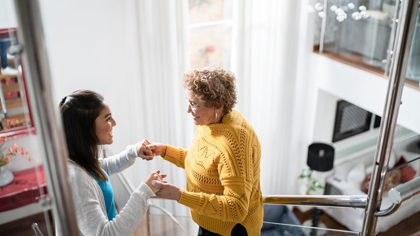 Nurse supporting senior patient walking up the stairs