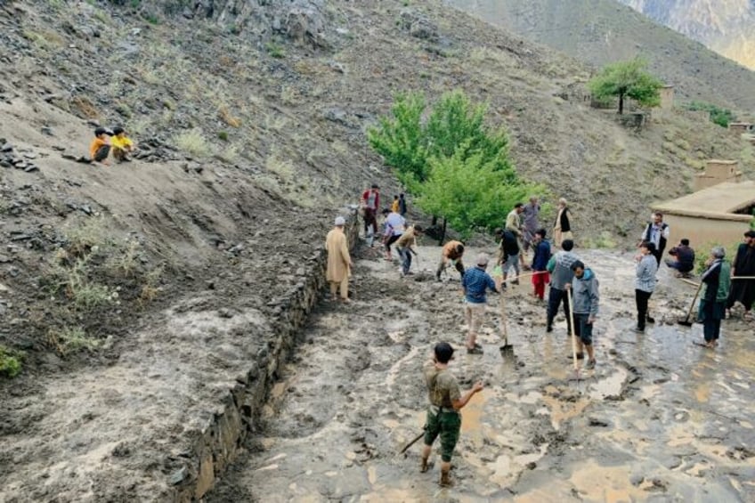 Afghan residents shovel mud following flash floods after heavy rainfall at Pesgaran villag