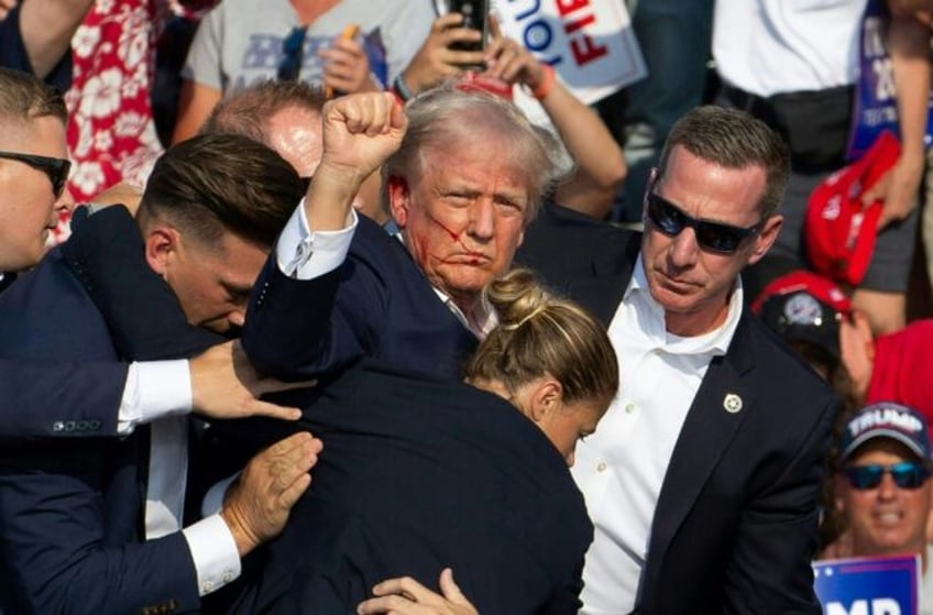 Republican candidate Donald Trump is seen with blood on his face surrounded by secret serv