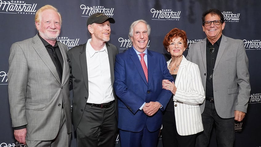 The cast of Happy Days today posing for a photo and smiling on the red carpet