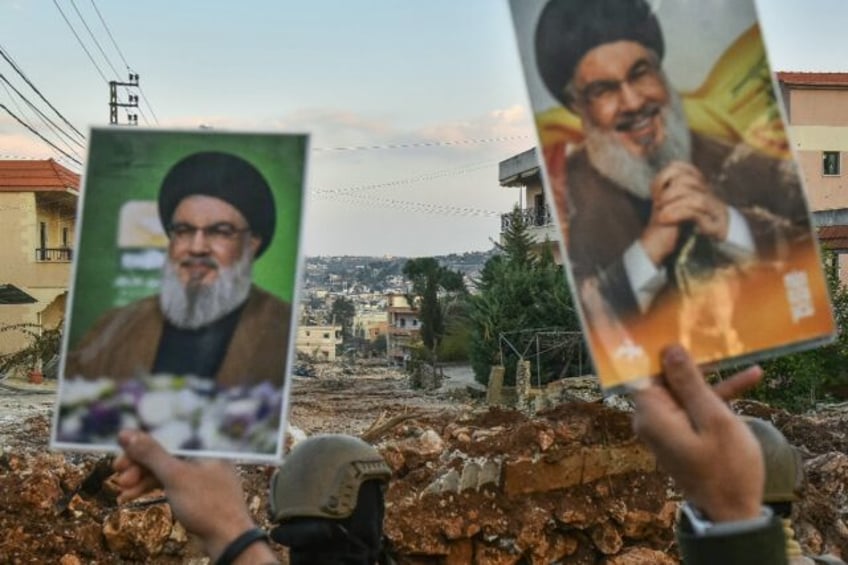 Residents of the southern Lebanese village of Aitaroun lift portraits of Hezbollah's slain