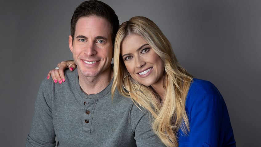 Tarek El Moussa in a grey shirt smiles next to wife Christina in a bright blue shirt in a promo for "Flip or Flop."