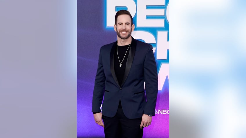 Tarek El Moussa smiling and wearing a dark suit