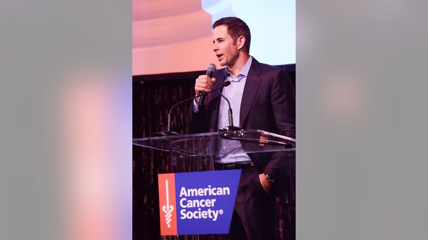 Tarek El Moussa speaking in front of a podium