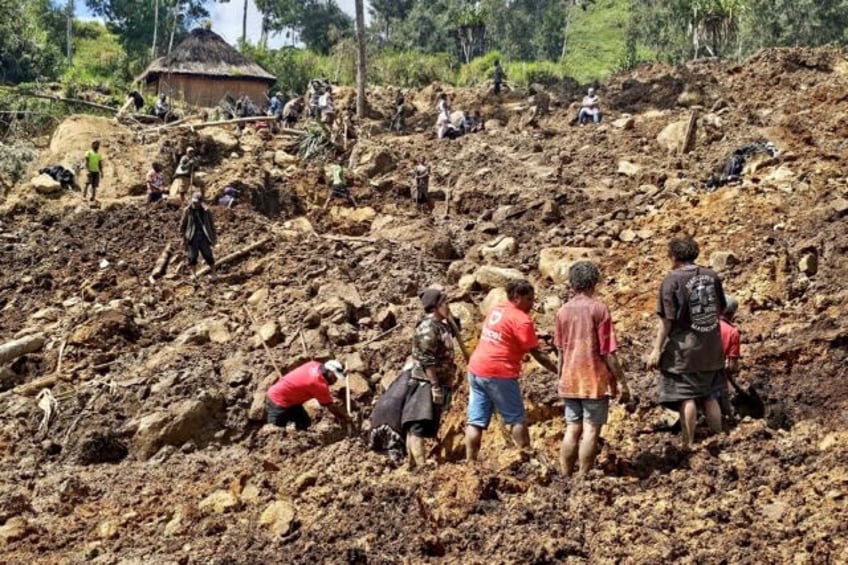 Locals dig during search and rescue efforts at the site of a landslide in Papua New Guinea