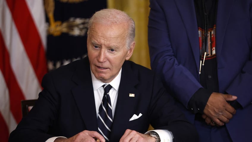 President Joe Biden signs papers at his desk