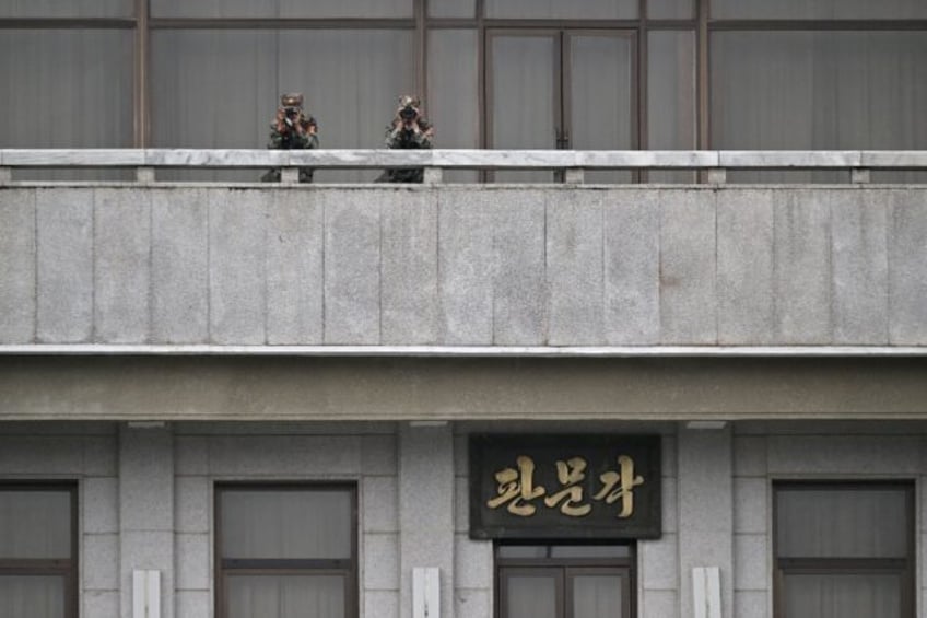 North Korean soldiers peering south from their side of the border at Panmunjom truce villa