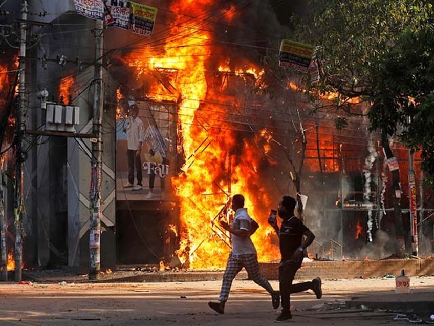 Men run past a shopping center which was set on fire by protesters during a rally against