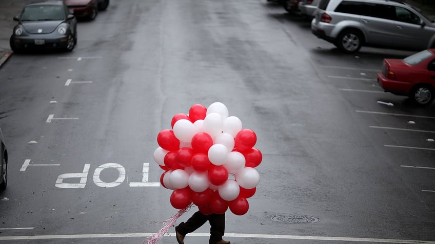 A man carries red and white balloons on Valentine's Day