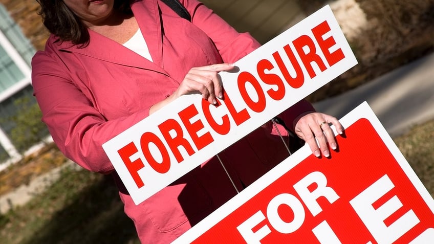 Real estate agent places a foreclosure sign outside a house