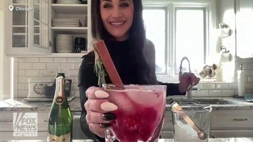 Briana DiTommaso holds her finished holiday cocktail in front of the camera.