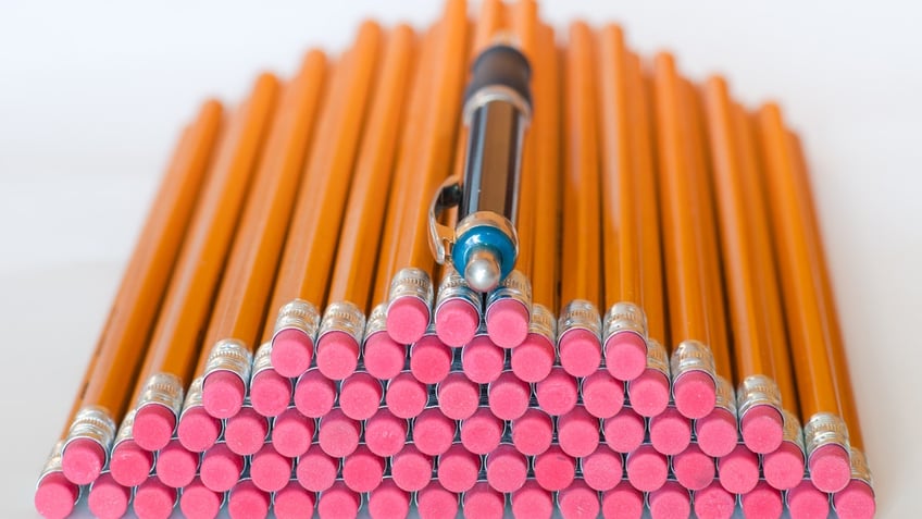 Stack of pencils with a pen on top