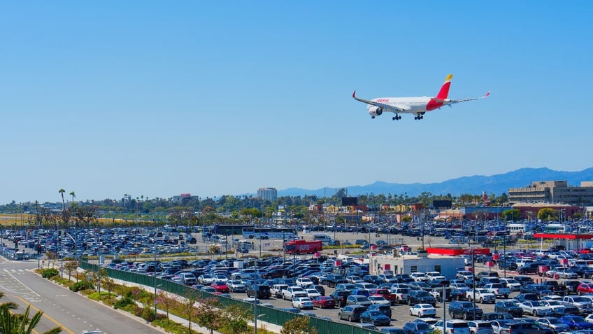 Los Angeles, California - April 9, 2024: Iberia Airlines plane soaring over the LAX Parking lot, set against the backdrop of a clear blue sky on a sunny day.