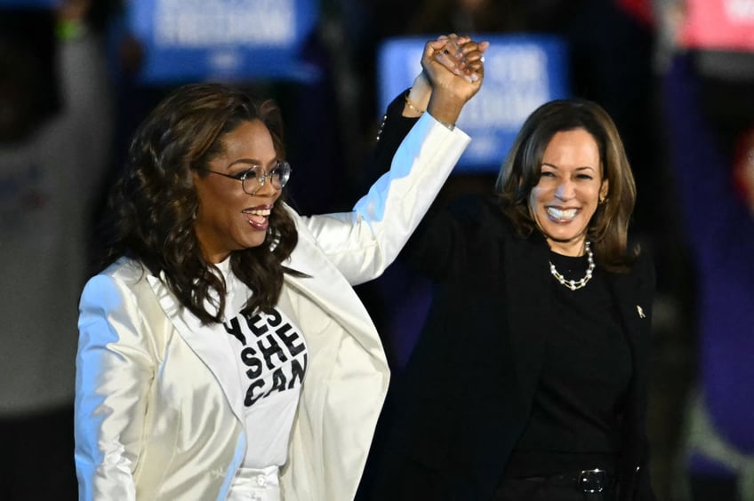 TOPSHOT - US producer and actress Oprah Winfrey (L) holds up US Vice President and Democratic presidential candidate Kamala Harris' hand as she arrive onstage during a campaign rally on the Benjamin Franklin Parkway in Philadelphia, Pennsylvania, on November 4, 2024. (Photo by ANGELA WEISS / AFP) (Photo by ANGELA WEISS/AFP via Getty Images)