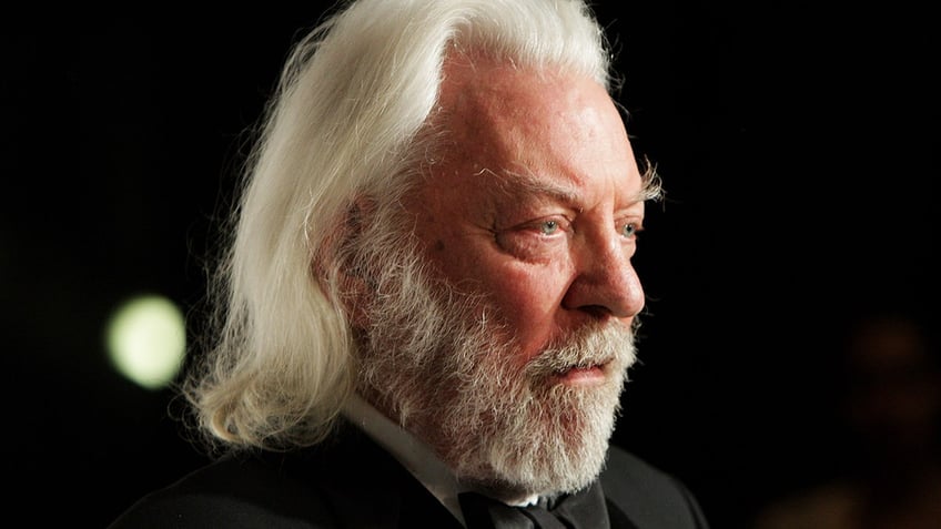 Donald Sutherland poses in the press room wearing black suit.