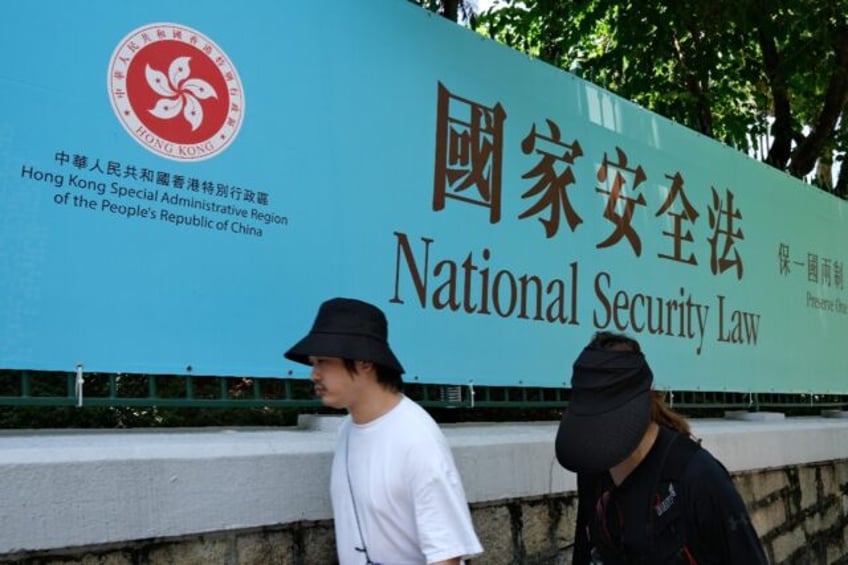 Pedestrians walk past a government public notice banner for the National Security Law in H