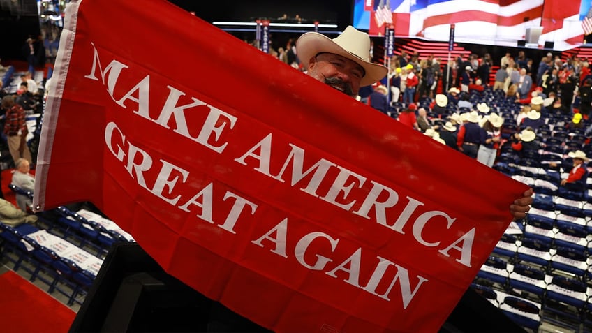 A man holds a "Make America Great Again" flag