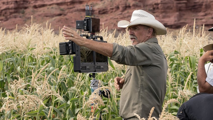 Kevin Costner wears a cowboy hat and green shirt while filming Horizon.