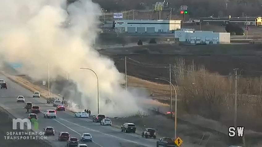 A hot air balloon crash site shows smoke billowing up into the air