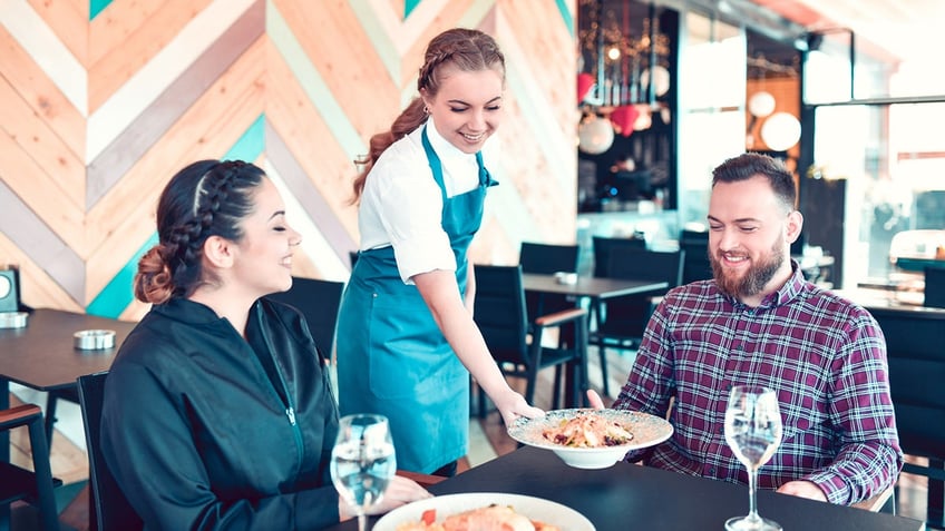 A couple being served a meal at a restaurant.