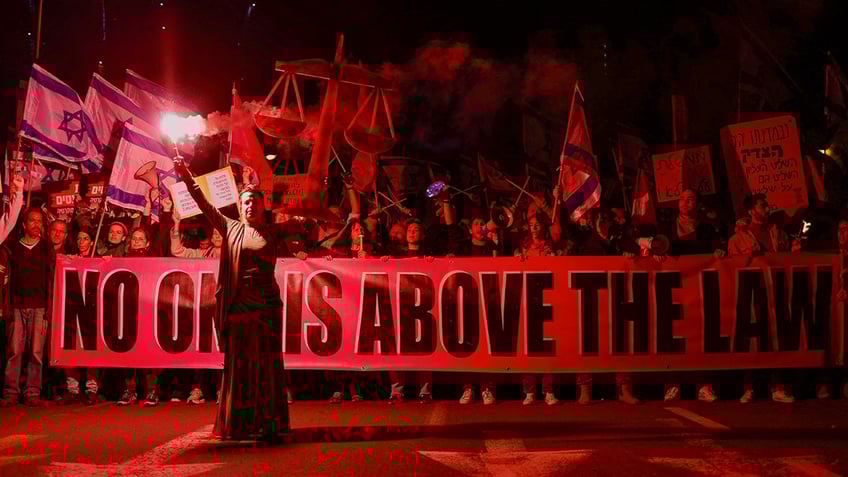 Israelis hold a banner reading "no one is above the law" during an anti-Netanyahu protest
