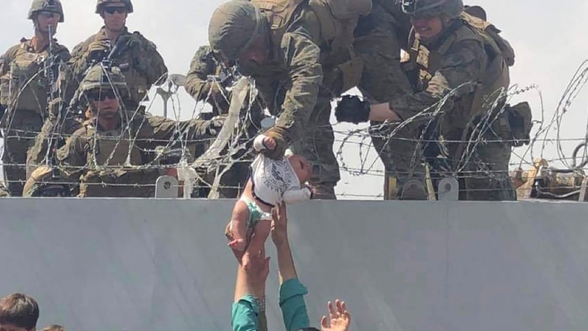 Baby over fence at Kabul Airport