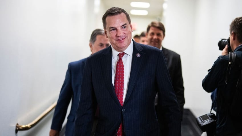 Richard Hudson smiling in hallway with others behind him