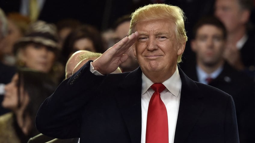 TOPSHOT - US President Donald Trump salutes during the presidential inaugural parade on January 20, 2017 in Washington, DC.