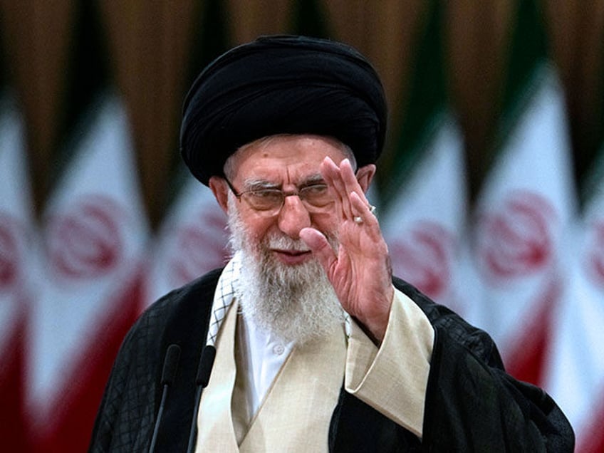 Iranian Supreme Leader Ayatollah Ali Khamenei waves after casting his vote for the preside