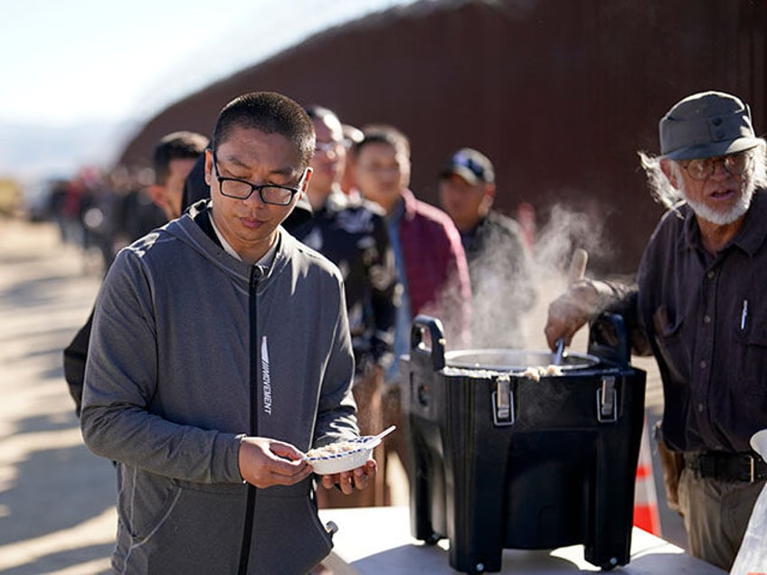 A man from China gets a bowl of oatmeal from a volunteer as he waits with others for proce