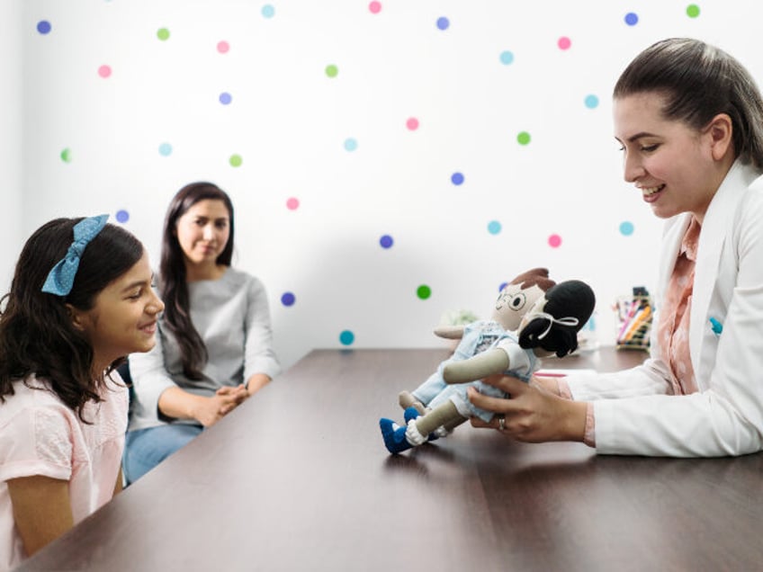 female psychologist or therapist showing dolls to girl patient