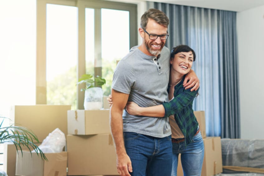 Shot of a happy couple embracing in their home on moving day