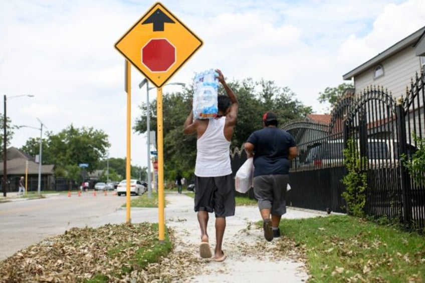 A man carries a container of water from a distribution center in Houston, Texas, on July 1