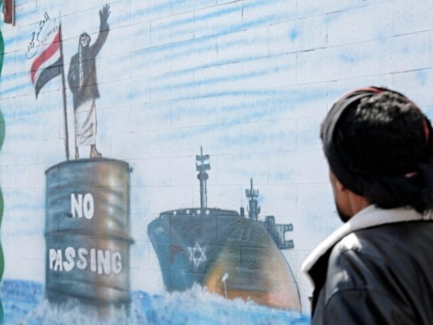 SANA'A, YEMEN - FEBRUARY 25: A man walks next to artworks depicting a Yemeni checkpoint st