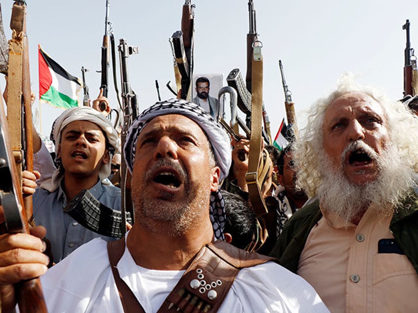 Demonstrators brandish rifles, flags of Yemen and Palestine, Houthi emblems and chant slog