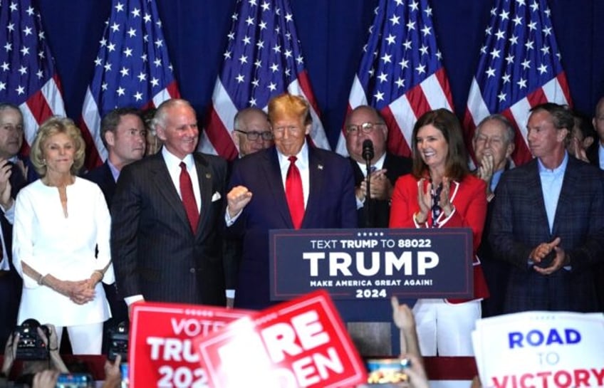 Former US president Donald Trump is flanked by supporters as he celebrates victory in Sout