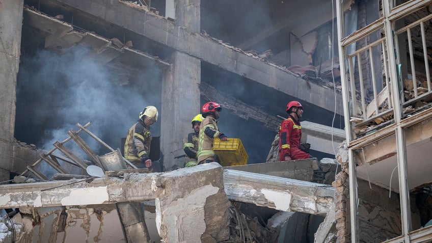Iranian firefighters work at the scene of a destroyed residential building due to Israeli attacks in Tehran, Iran, on June 13, 2025. 