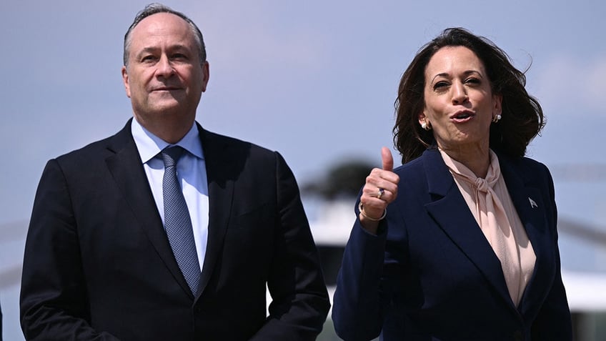 US Vice President and 2024 Democratic presidential candidate Kamala Harris and Second Gentleman Doug Emhoff wave as they board Air Force Two