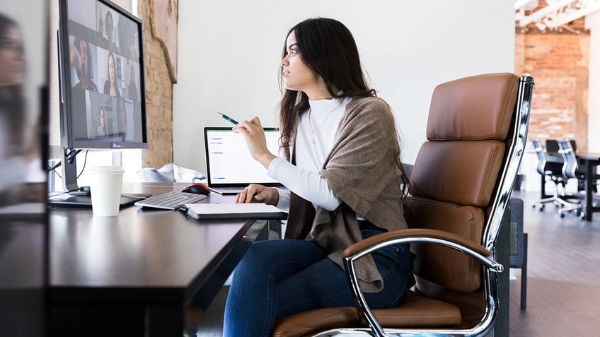 woman sits at desk in office on video call