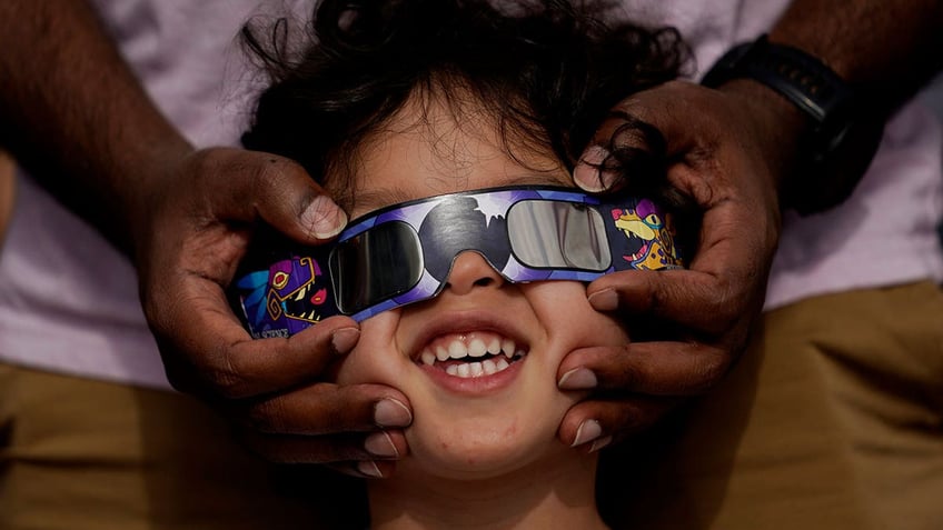 Child wearing eclipse glasses