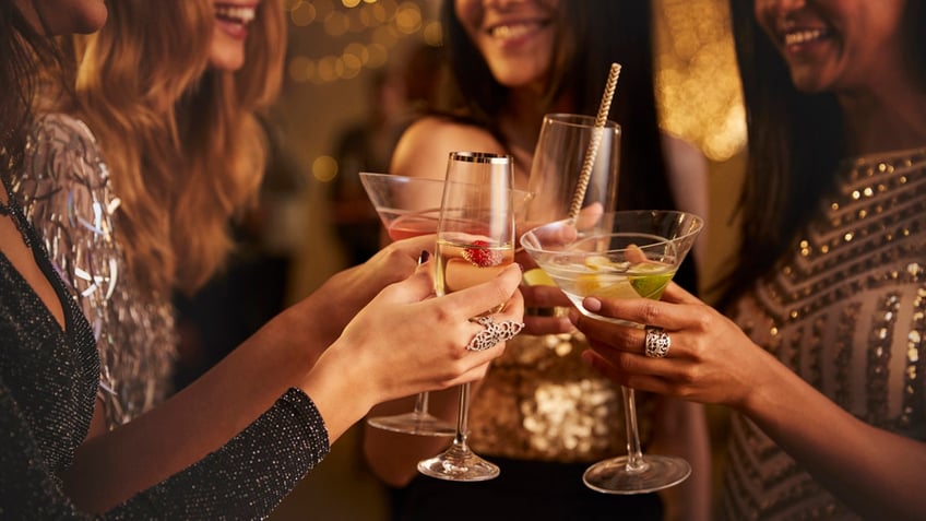 Group of friends toasting with various types of cocktails.