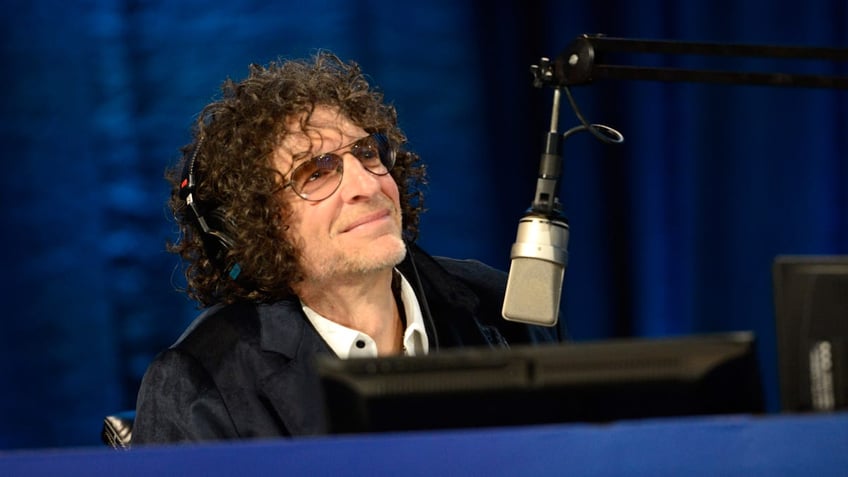 Howard Stern looks up with his headphones on while recording his show