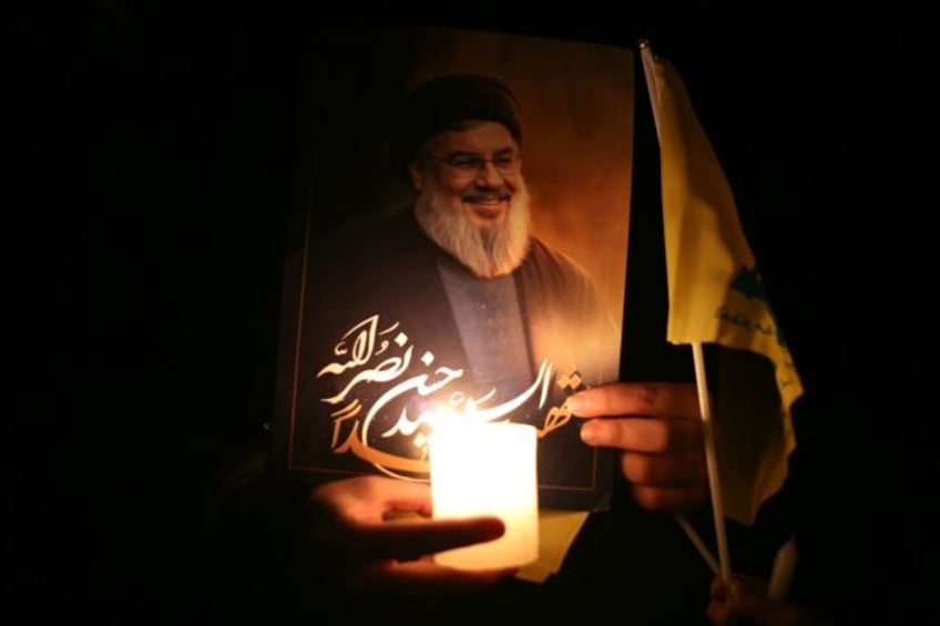 A mourner carries a candle and a portrait of slain Hezbollah chief Hassan Nasrallah during