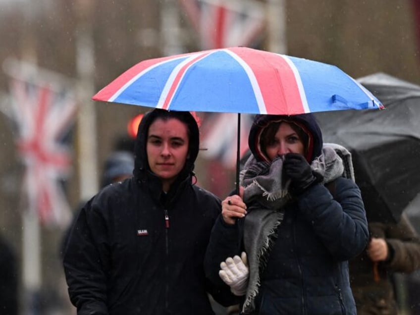 People shelter under an umbrella in the rain on The Mall in London on December 7, 2024, as