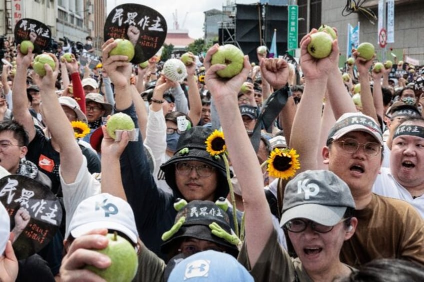 People hold up guavas as they take part in a protest ahead of the inauguration ceremony of