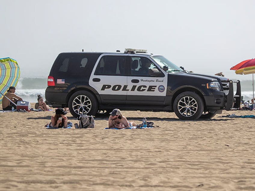 Huntington Beach police patrol the beach near the pier as thousands of beach-goers enjoy a