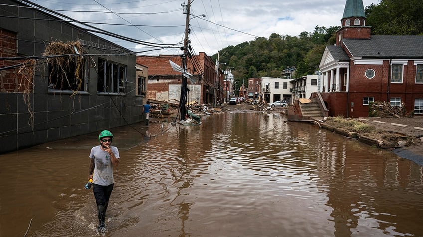 man wades through helene waters in NC