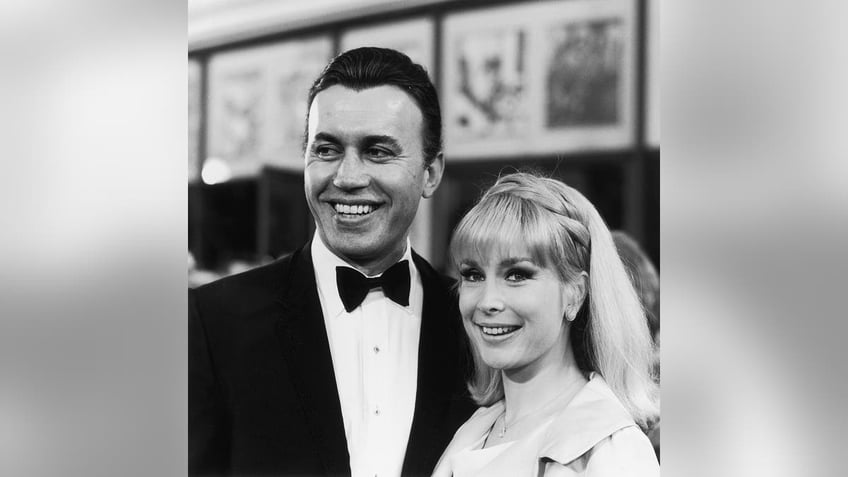 Barbara Eden smiling next to Michael Ansara who is wearing a tux.